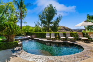 Lagoon-style pool and elevated spa at West Valley Estate with panoramic canyon views and luxury chaise lounge seating.