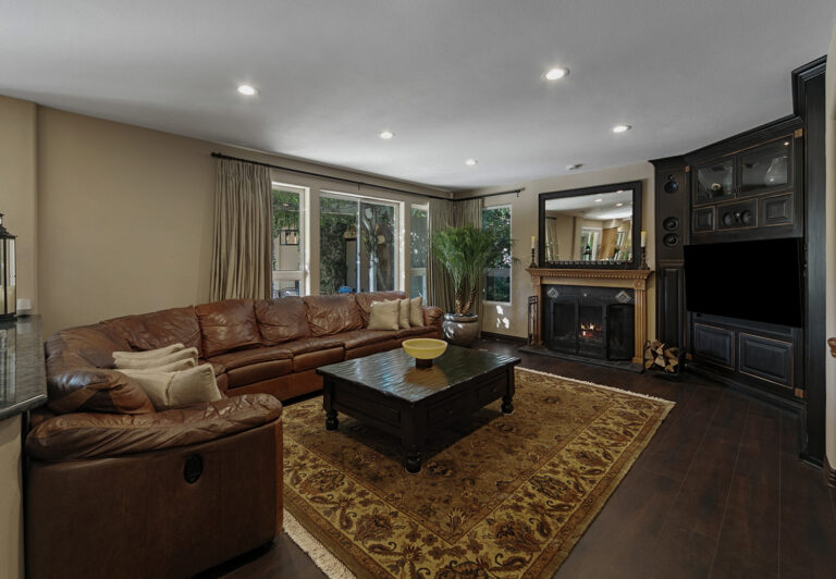 Cozy family room with fireplace, custom built-in entertainment center, leather sectional, and hardwood floors at West Valley Estate.