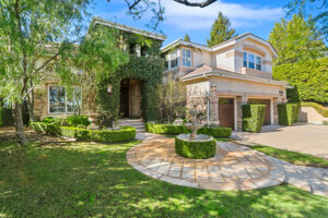 Front exterior of the West Valley Estate in West Hills featuring lush landscaping, ivy-covered stone entry with fountain, and a 4-car garage.